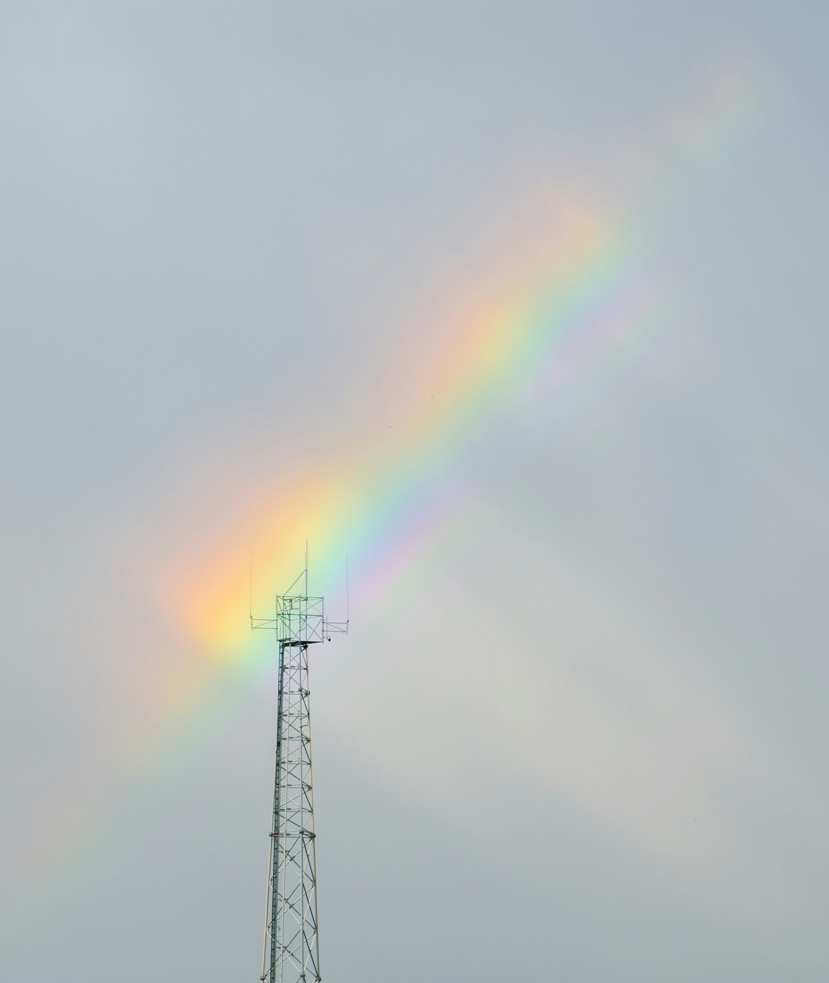 black metal tower under rainbow